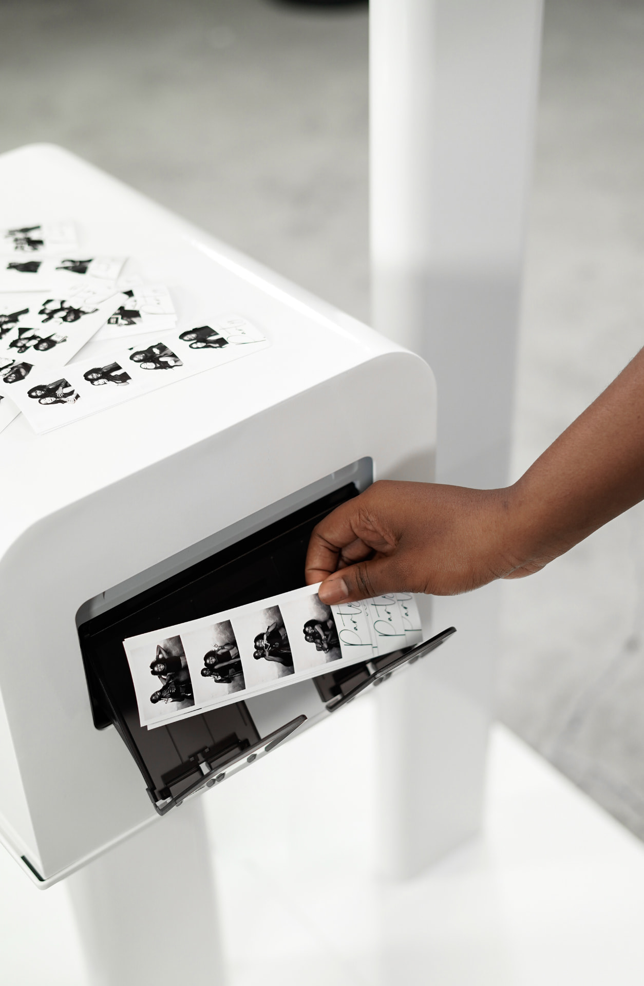 A guest pulling a fresh black and white photo strip from the printer